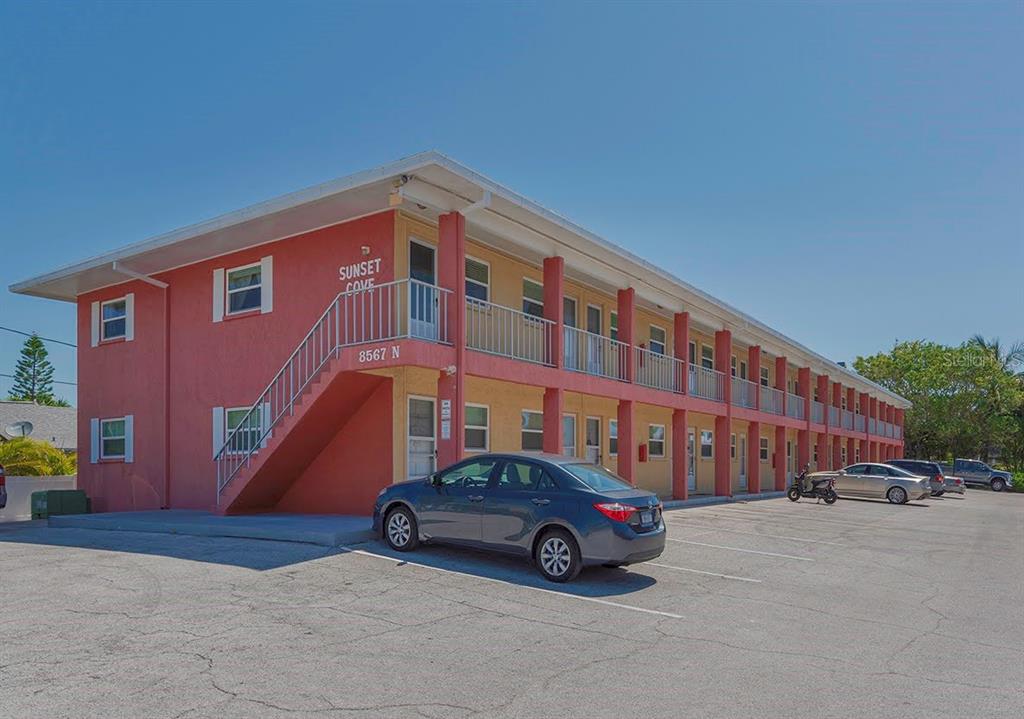 A two-story, pink and yellow apartment building features an exterior staircase and a parking lot — 8567 W GULF BOULEVARD UNIT 3N, ST PETERSBURG, FL
