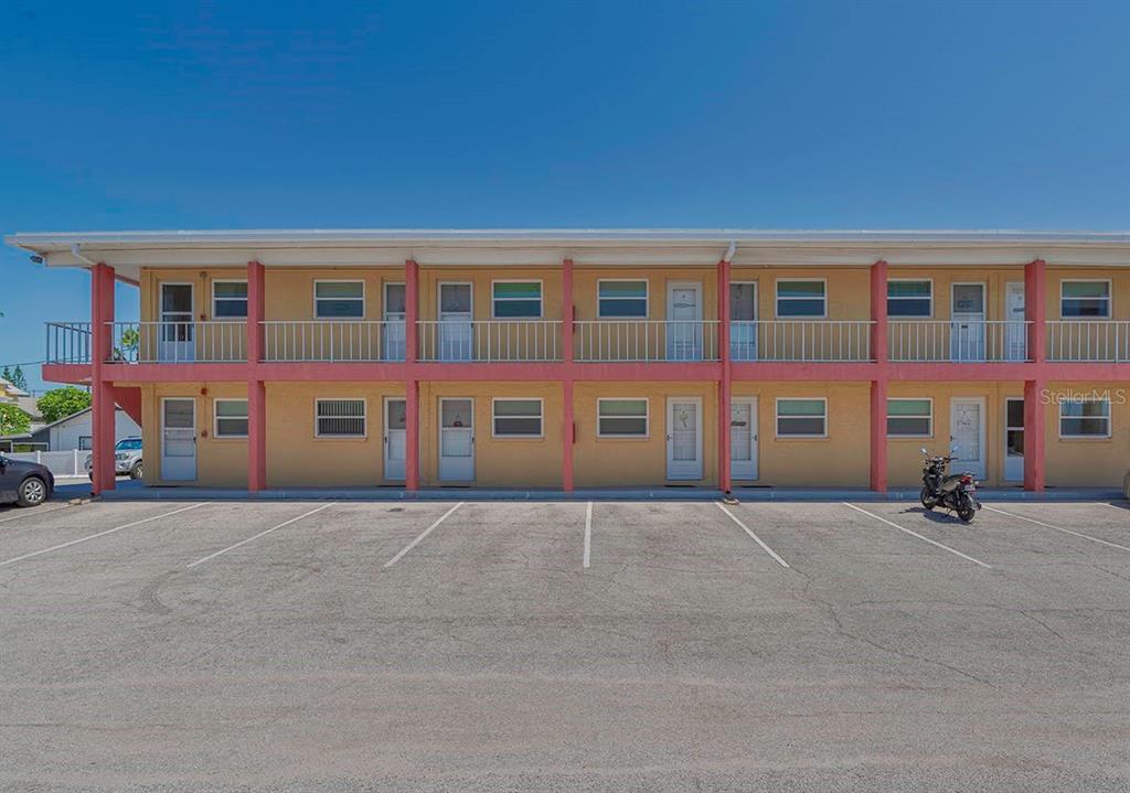 A two-story motel building with yellow stucco walls, pink support columns, and a parking lot — 8567 W GULF BOULEVARD UNIT 3N, ST PETERSBURG, FL