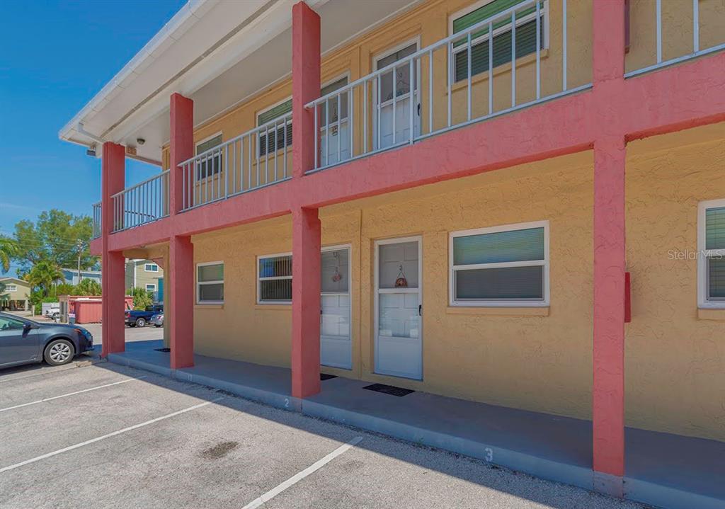 A two-story yellow apartment building with a covered parking area and exterior staircases — 8567 W GULF BOULEVARD UNIT 3N, ST PETERSBURG, FL