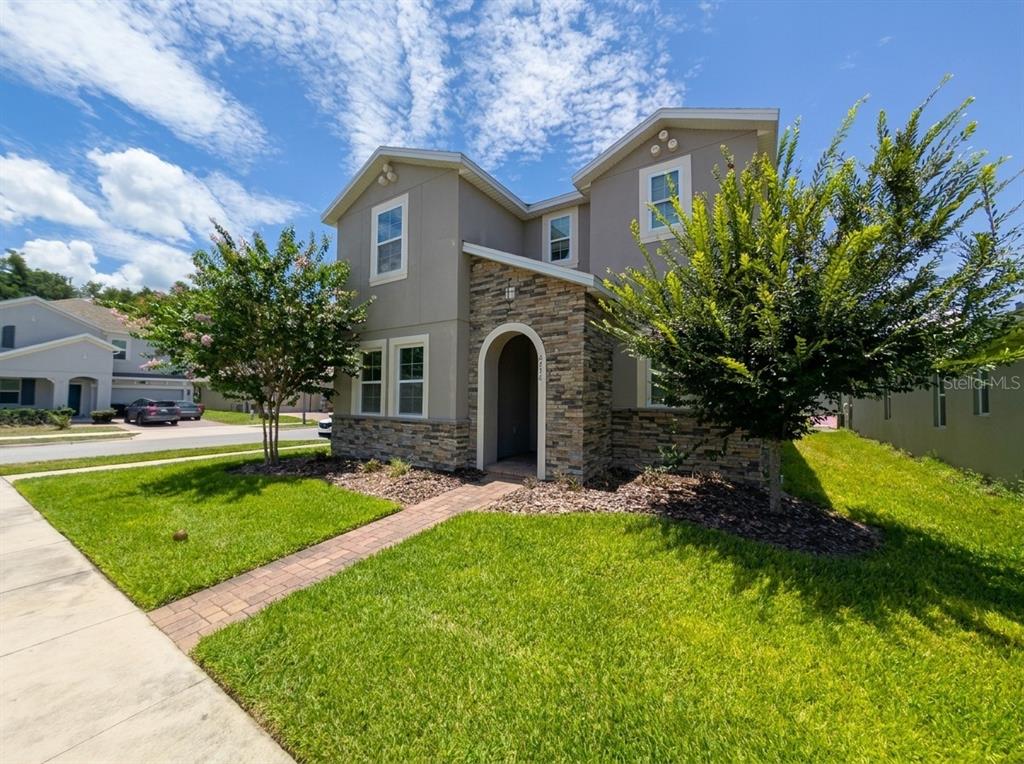 A two-story house with a stone facade, arched entryway, and a paved walkway — 2275 ABILIA ALLEY, APOPKA, FL