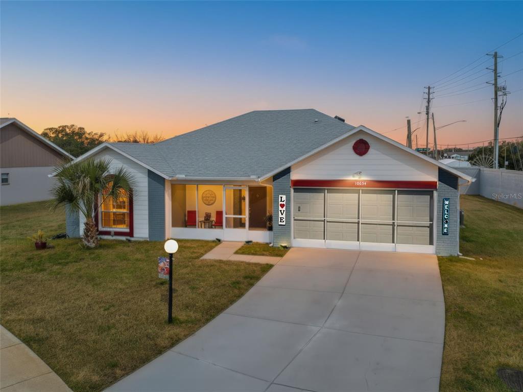 A single-story house with a gray roof, blue brick accents, and a screened-in front porch — 10654 FALLEN LEAF LANE, PORT RICHEY, FL