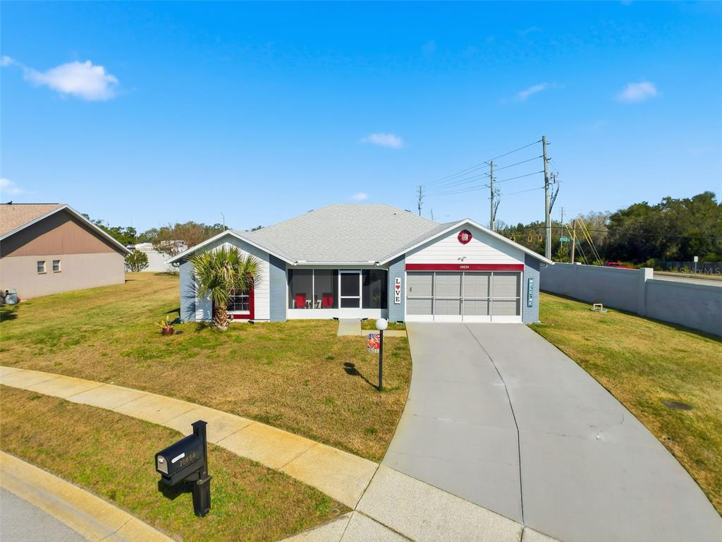 A single-story house with a gray exterior, a screened front porch, and a concrete driveway — 10654 FALLEN LEAF LANE, PORT RICHEY, FL