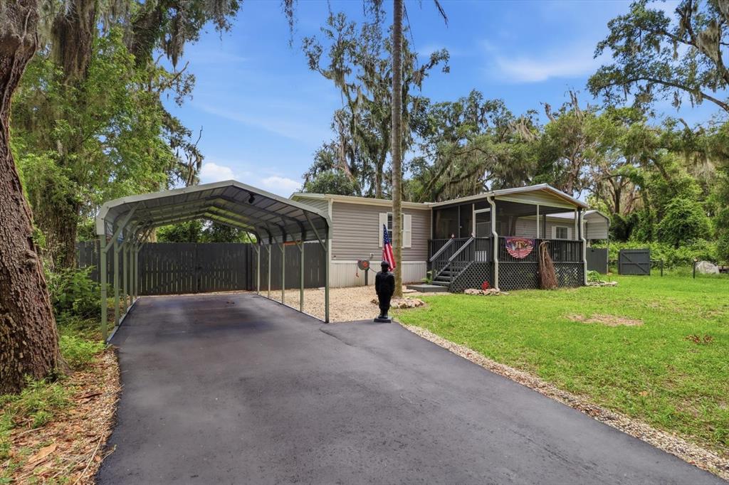 A single-story home with a metal carport, screened porch, and a paved driveway — 4370 E AMHERST STREET, HERNANDO, FL