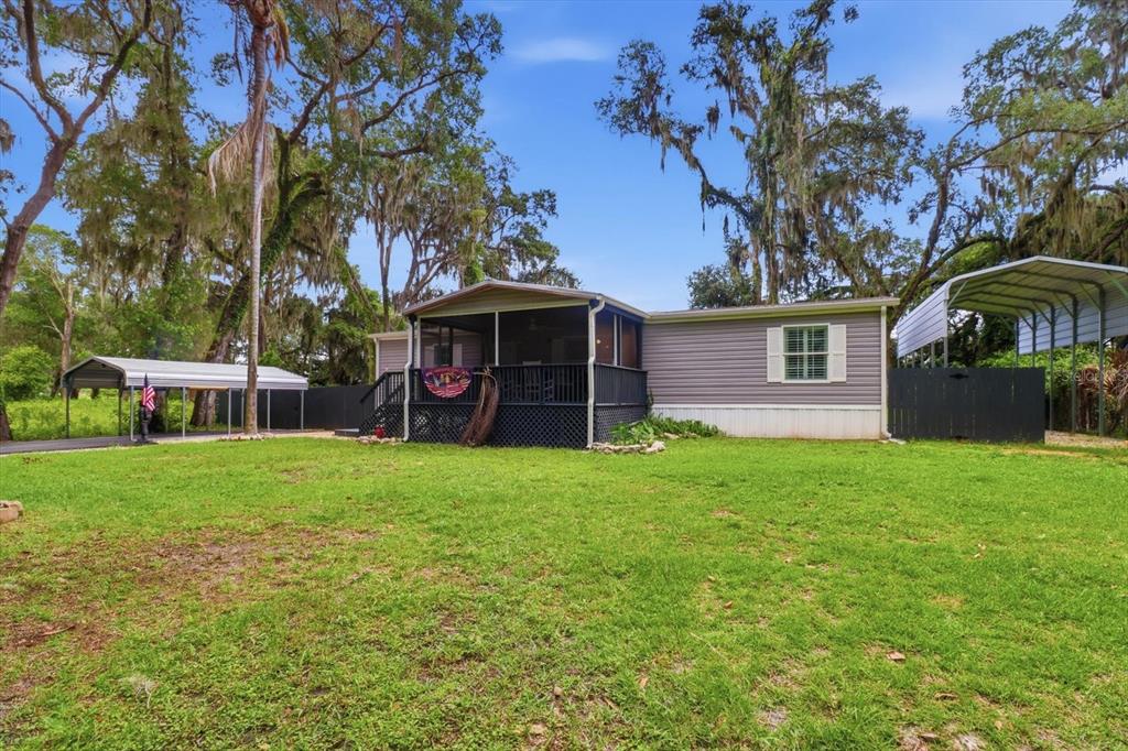 A single-story manufactured home with a screened porch and two metal carports on a lawn — 4370 E AMHERST STREET, HERNANDO, FL
