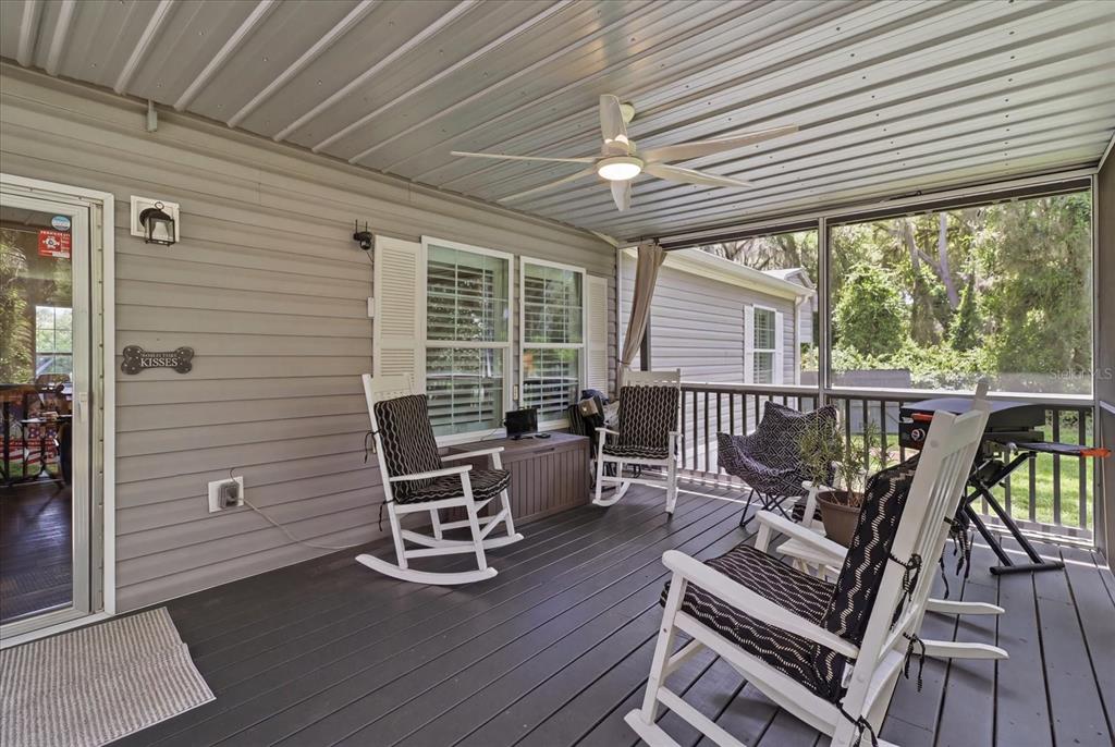 A covered porch features dark wood decking, a ceiling fan, and several rocking chairs — 4370 E AMHERST STREET, HERNANDO, FL