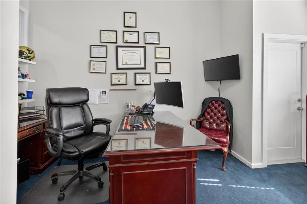 A home office features a glass-topped desk, leather chairs, and framed certificates on the wall — 10225 ULMERTON ROAD UNIT 12B, LARGO, FL