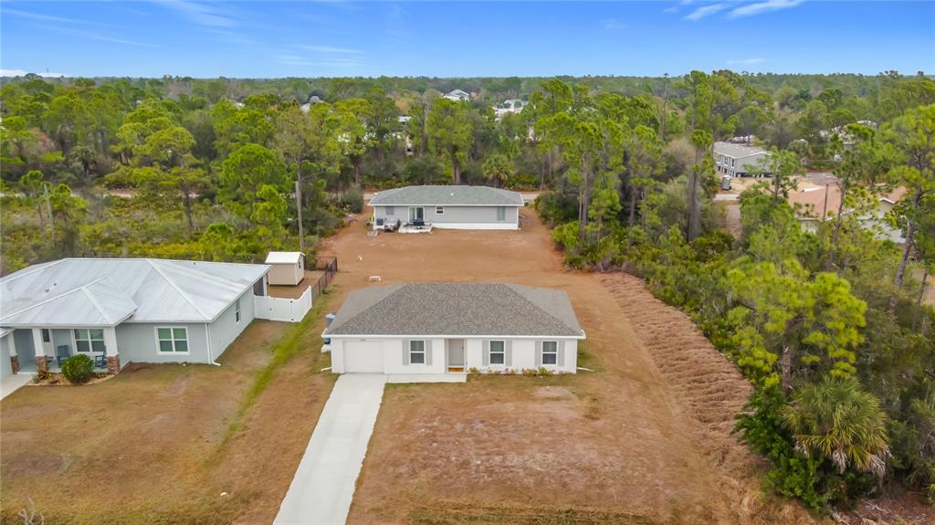 An aerial view shows two single-story houses with gray roofs situated on a wooded lot — 23300 AIRWAY AVENUE, PORT CHARLOTTE, FL