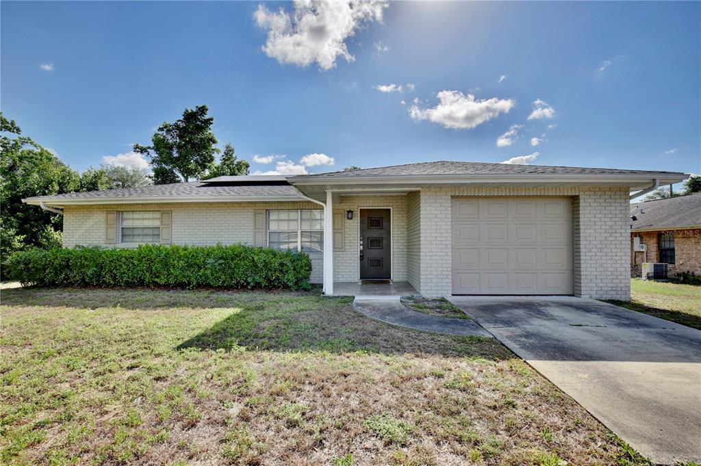 A single-story brick house with a front-facing garage, a covered entryway, and a front lawn — 1847 FAYETTEVILLE AVE, DELTONA, FL