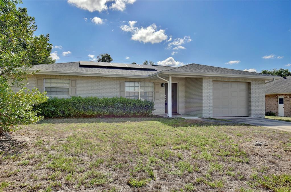 A single-story brick house with a garage, solar panels, and a front lawn — 1847 FAYETTEVILLE AVE, DELTONA, FL