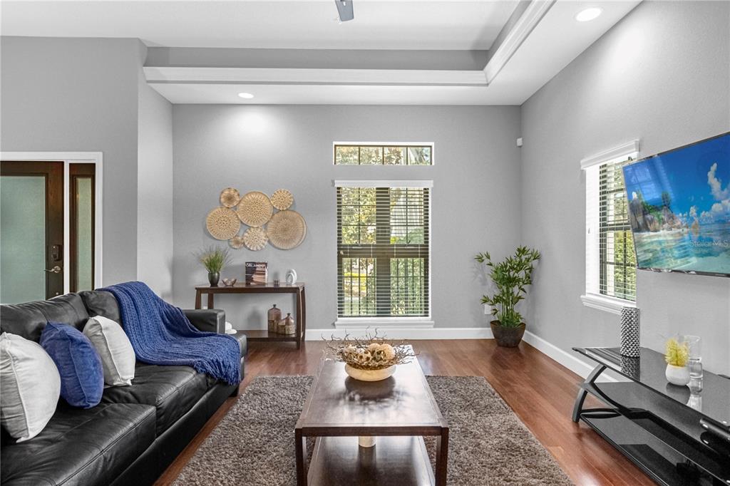 A living room features a black leather sofa, a coffee table, and a wall-mounted television — 8501 KEDIAMAN AVENUE UNIT 8501, ORLANDO, FL