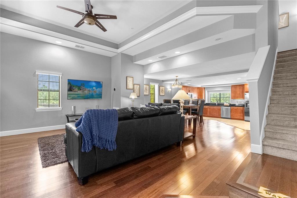 A living room with hardwood floors, a black leather sofa, and an open kitchen beyond — 8501 KEDIAMAN AVENUE UNIT 8501, ORLANDO, FL