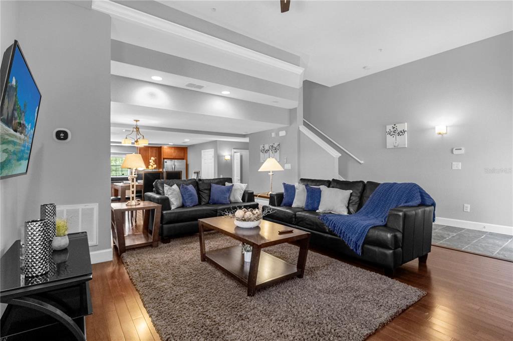 A living room with hardwood floors, a large area rug, and two black leather sofas — 8501 KEDIAMAN AVENUE UNIT 8501, ORLANDO, FL