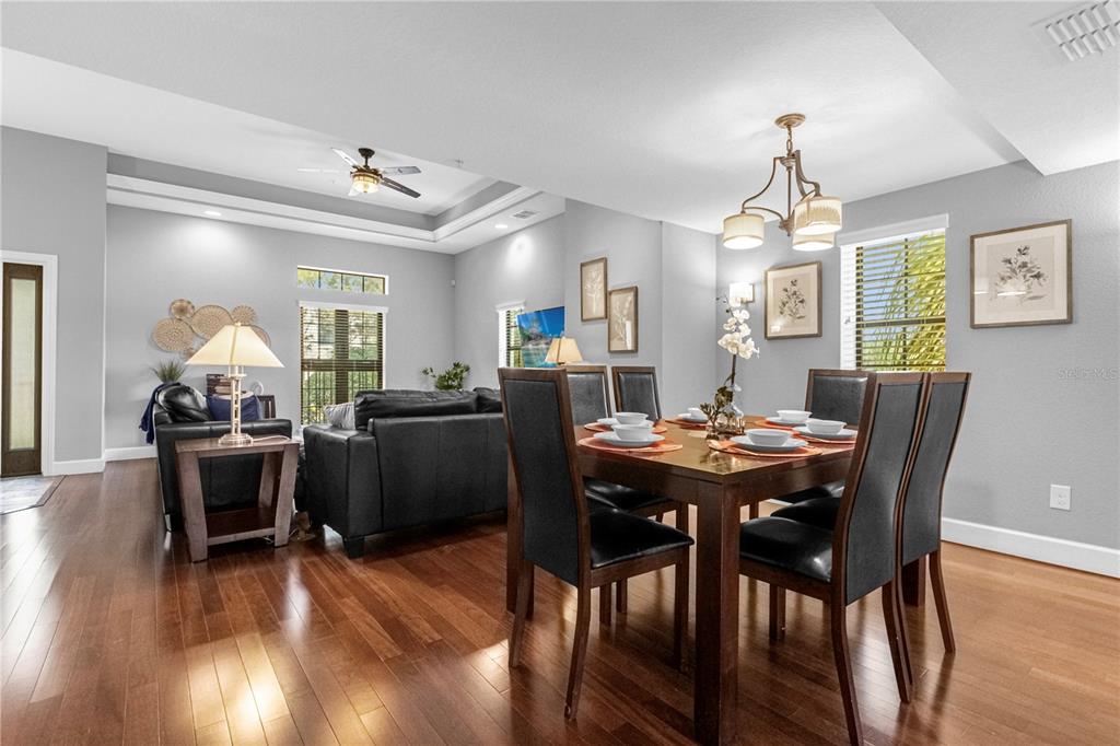 A dining area with a wooden table and chairs sits adjacent to a living room — 8501 KEDIAMAN AVENUE UNIT 8501, ORLANDO, FL