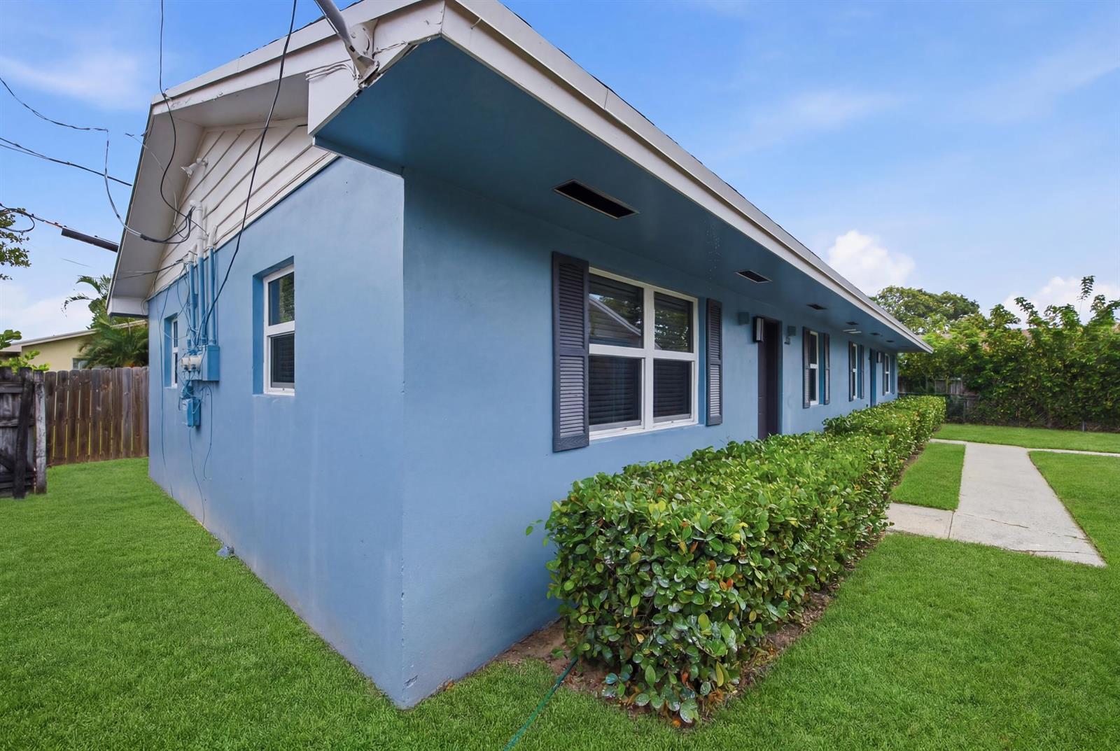 A blue exterior wall of a single-story building features a row of windows and hedges — 355 Wickline Boulevard, Lantana FL 33462, LANTANA, FL