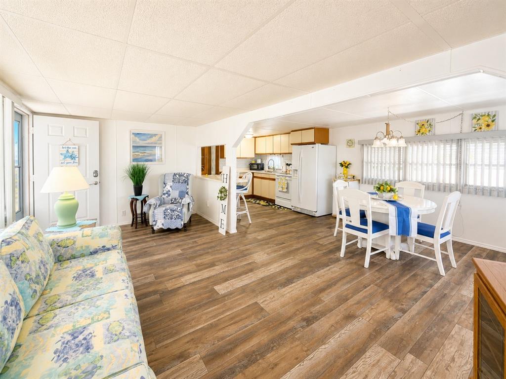 An open-concept living and dining area features wood-look flooring, white walls, and coastal decor — 1912 IOWA AVENUE, BRADENTON, FL