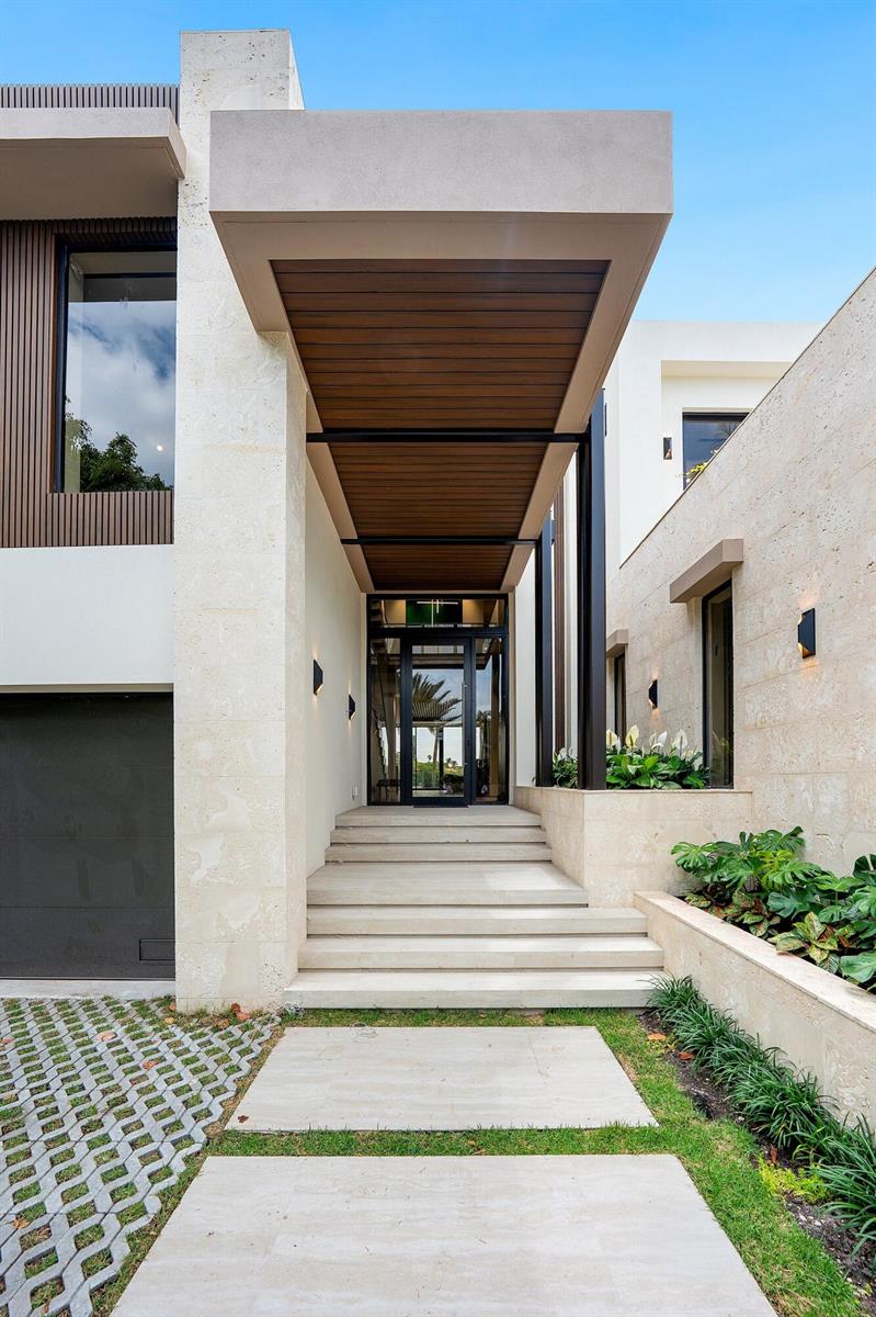 A modern home exterior features a stone facade, a covered entryway, and concrete steps — 5 Barefoot Lane, Lantana FL 33462, LANTANA, FL