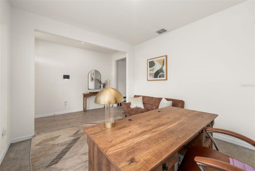 A home office features a wooden desk, a brown sofa, and a gold table lamp — 1443 NW 140TH WAY, NEWBERRY, FL