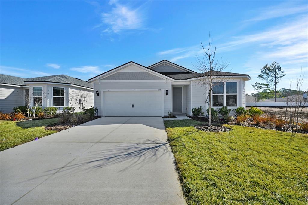 A single-story house features light gray siding, a two-car garage, and a concrete driveway — 83 LAKE MANATEE DRIVE, PALM COAST, FL