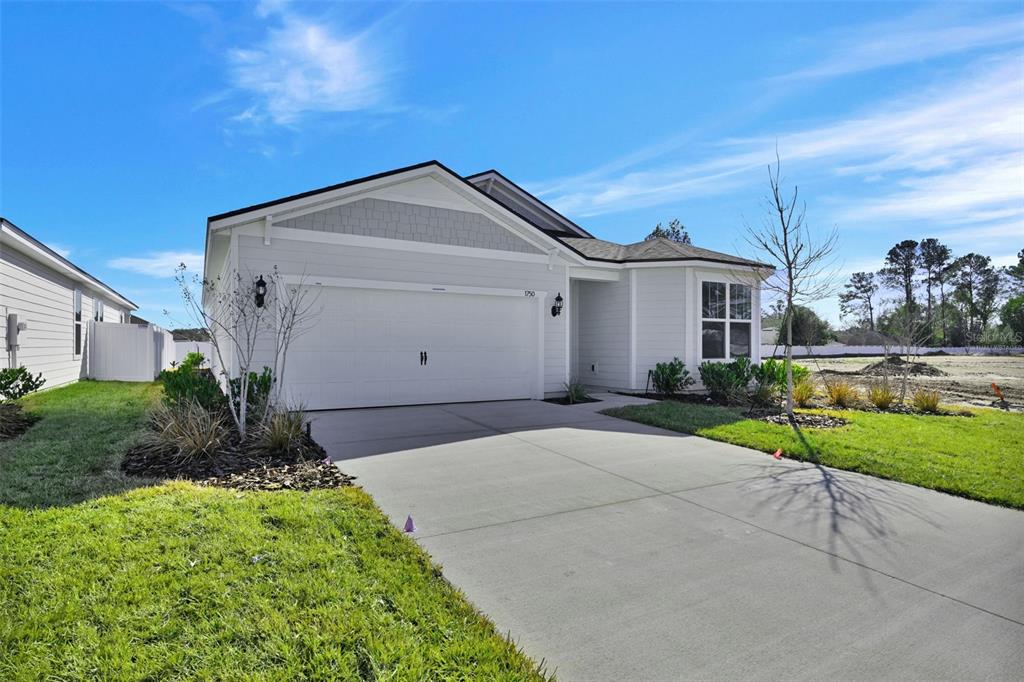 A single-story house with light gray siding, a two-car garage, and a concrete driveway — 83 LAKE MANATEE DRIVE, PALM COAST, FL