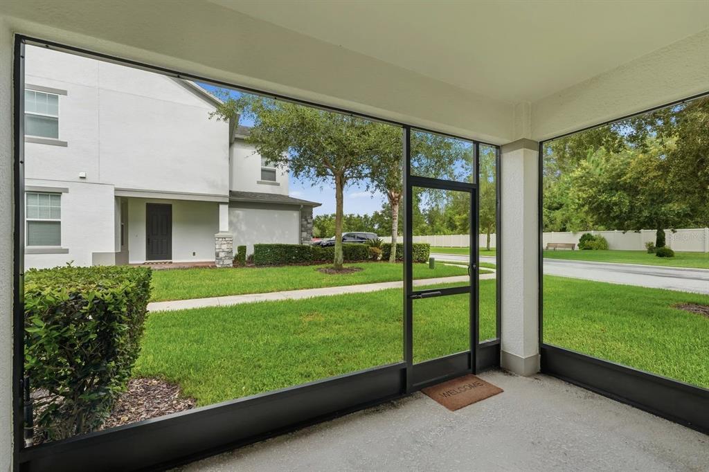 A view from a screened-in porch looking out onto a grassy lawn and neighboring house — 15691 ORANGE HARVEST LOOP, WINTER GARDEN, FL