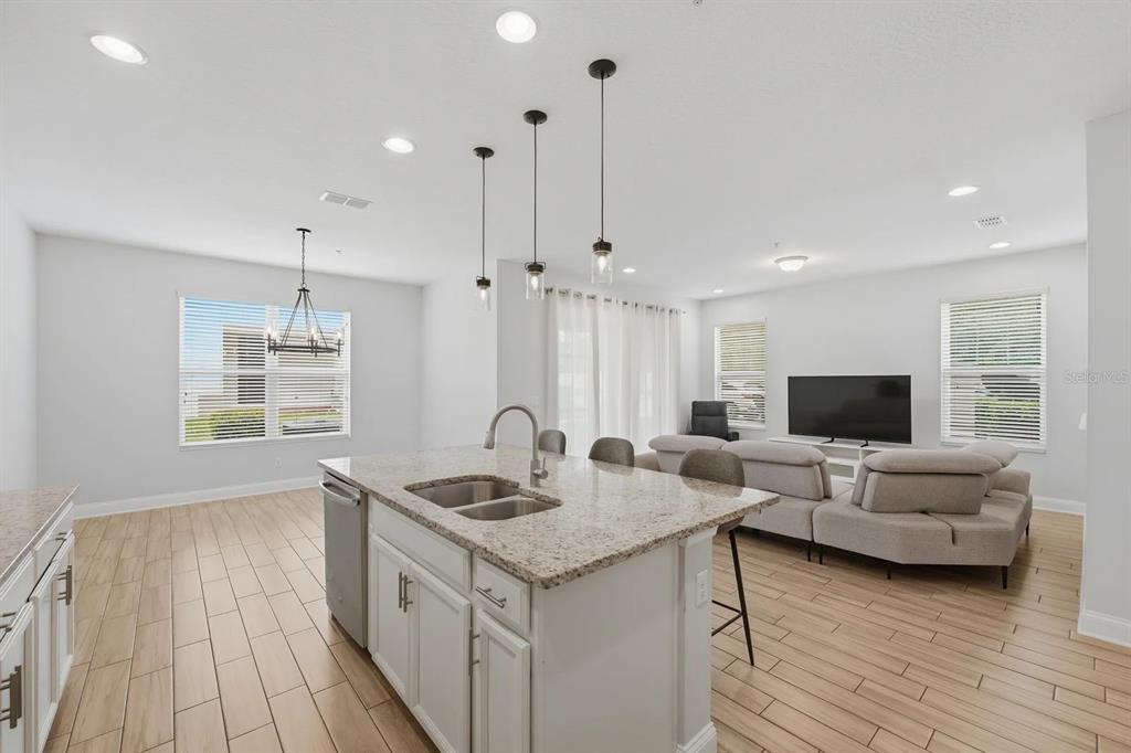 A kitchen island with granite countertops sits in an open-concept living area with tile flooring — 15691 ORANGE HARVEST LOOP, WINTER GARDEN, FL