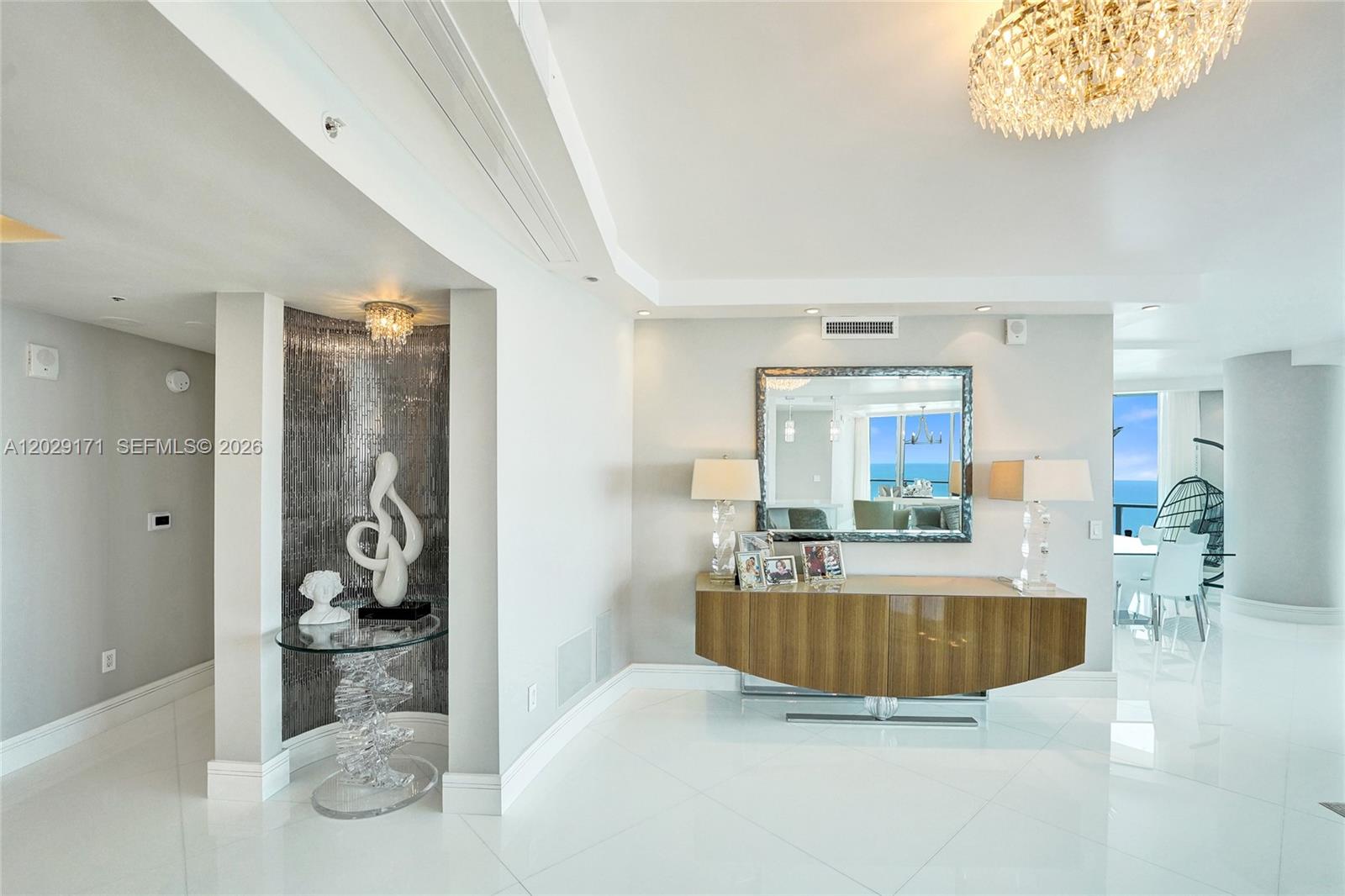 A modern foyer features a glass console table, a wood sideboard, and a crystal chandelier — 3101 S Ocean Dr # 2208, Hollywood FL 33019, HOLLYWOOD, FL