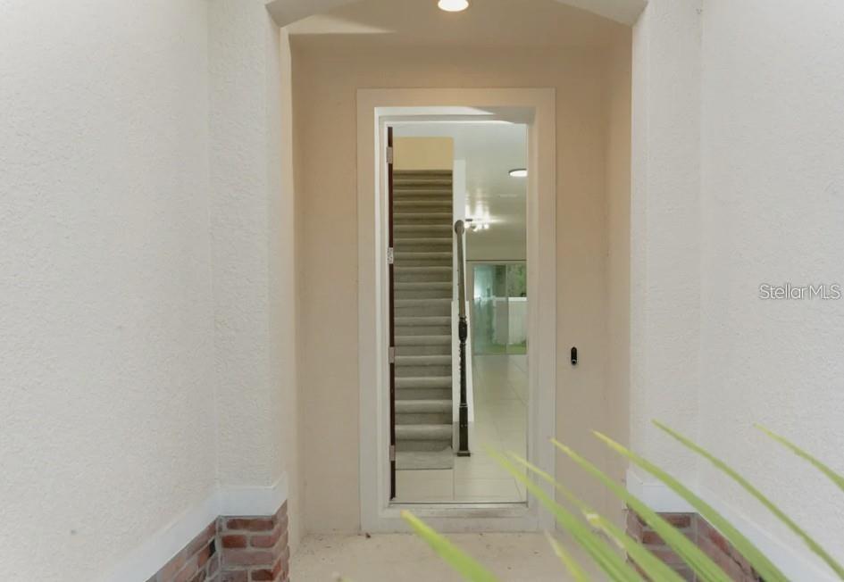 A view through an open doorway shows an interior staircase with carpeted steps — 81 MAYO COURT, OVIEDO, FL