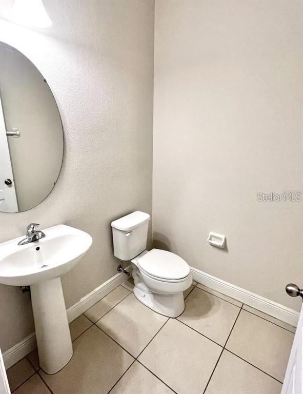 A half bathroom features a pedestal sink, an oval mirror, and a white toilet — 81 MAYO COURT, OVIEDO, FL