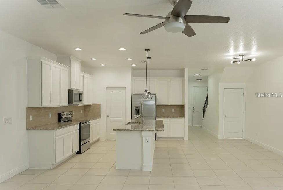 A kitchen features white cabinets, granite countertops, a center island, and stainless steel appliances — 81 MAYO COURT, OVIEDO, FL