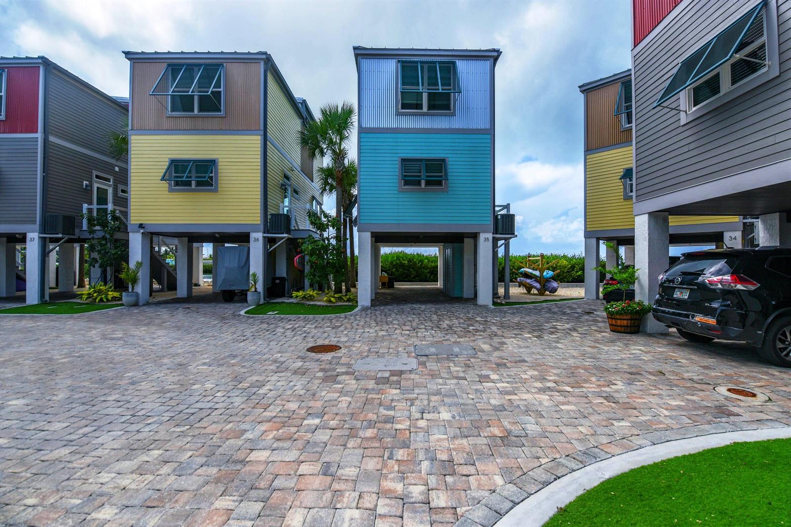 A paved courtyard sits between several elevated, colorful houses with metal siding and stilt foundations — 101 11th Street # 35, Marathon FL 33050, MARATHON, FL