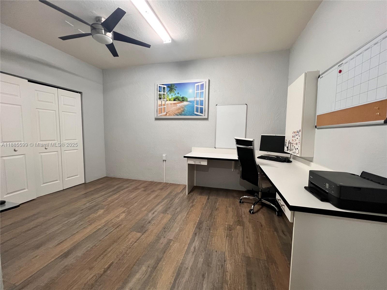 A home office features wood-look flooring, a white desk, a ceiling fan, and a whiteboard — 159 SE 34th Ave, Homestead FL 33033, HOMESTEAD, FL