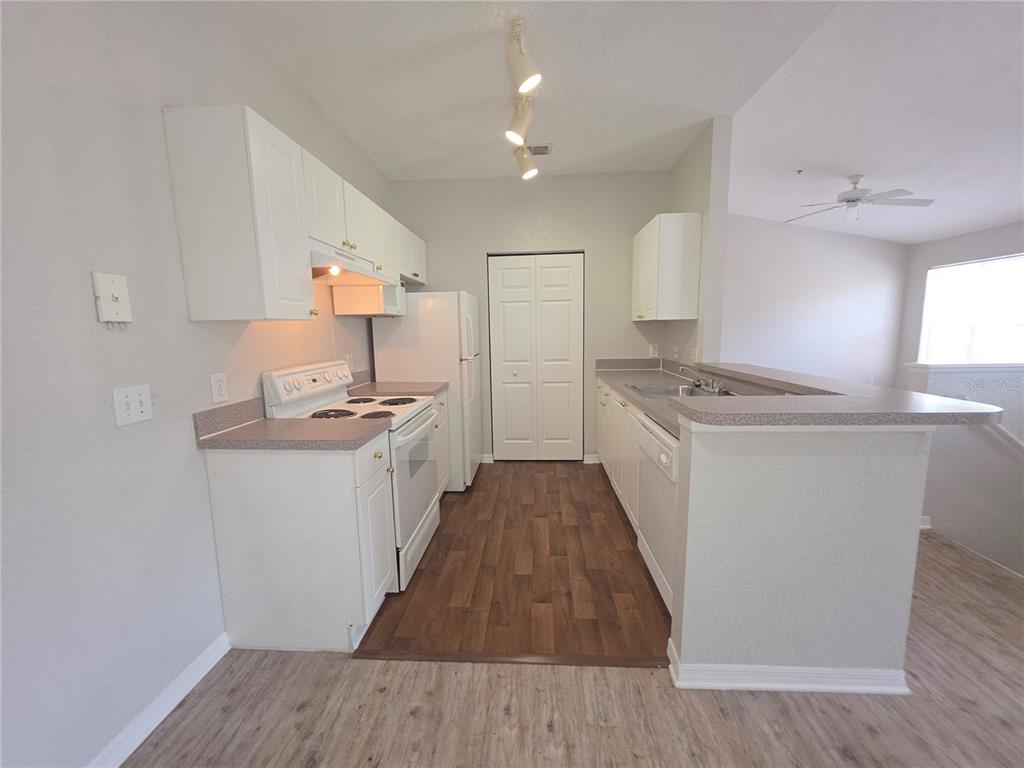 A kitchen features white cabinets, white appliances, a breakfast bar, and wood-look flooring — 852 GRAND REGENCY POINT UNIT 202, ALTAMONTE SPRINGS, FL