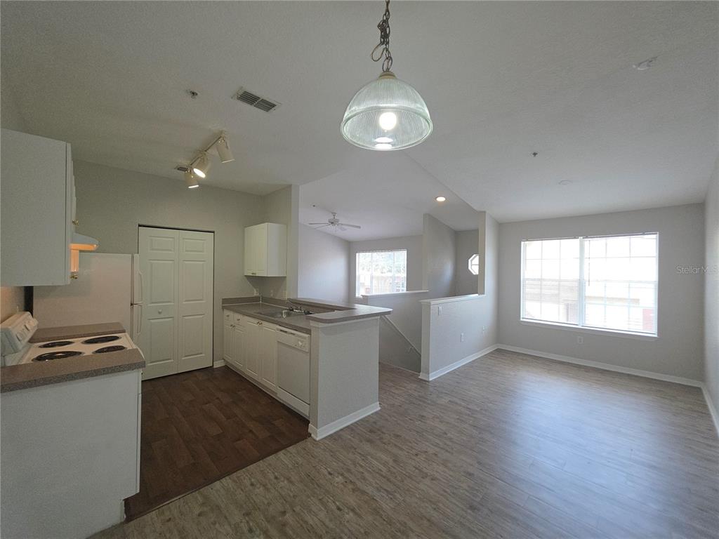 An open-concept kitchen and living area feature light wood-look flooring and white cabinetry — 852 GRAND REGENCY POINT UNIT 202, ALTAMONTE SPRINGS, FL