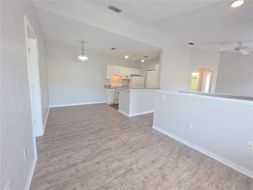 An open-concept kitchen and dining area features light wood-look flooring and white cabinetry — 852 GRAND REGENCY POINT UNIT 202, ALTAMONTE SPRINGS, FL