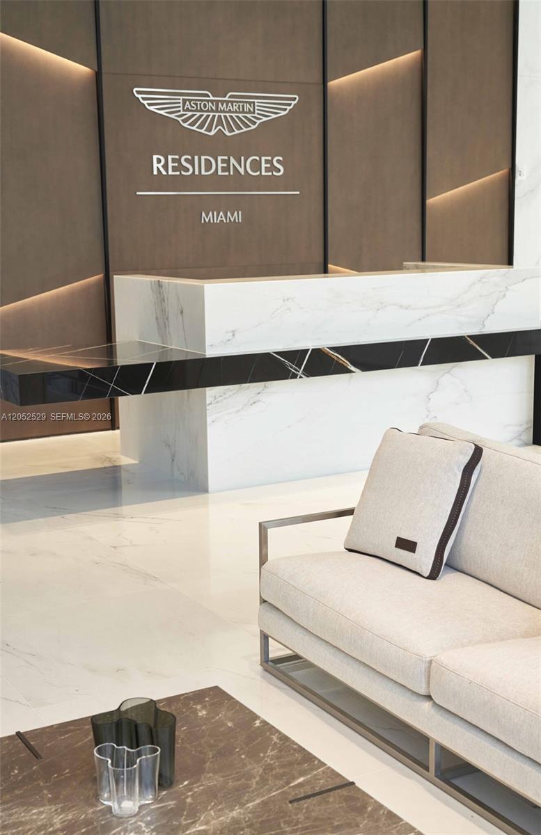 A modern lobby features a marble reception desk, a sofa, and Aston Martin Residences branding — 300 Biscayne Boulevard Way # 1705W, Miami FL 33131, MIAMI, FL