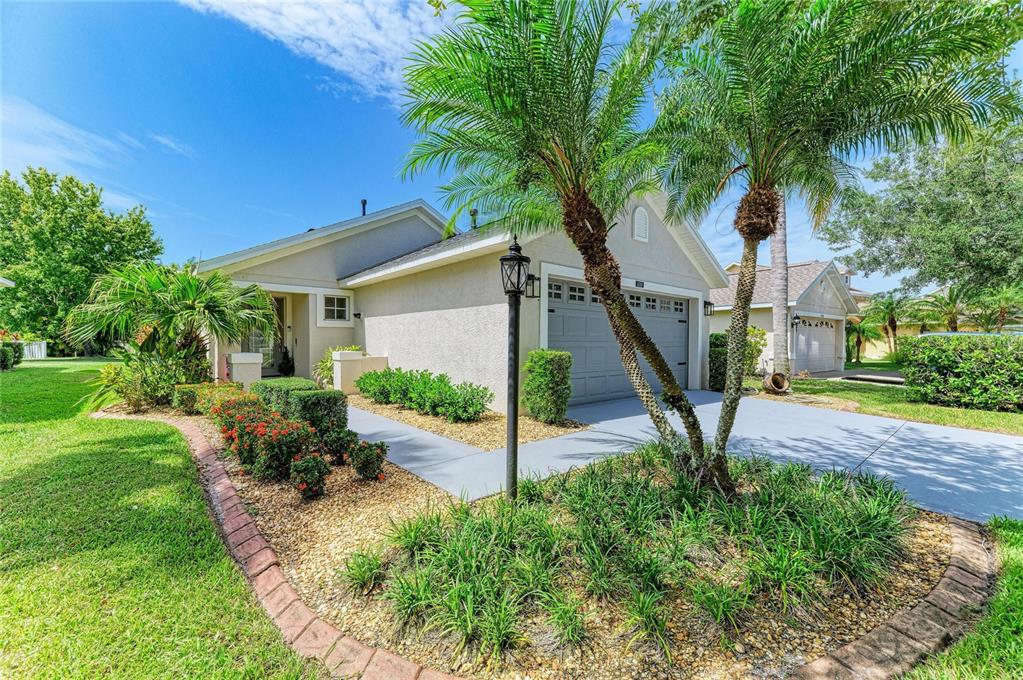 A single-story house with a gray garage, palm trees, and landscaped garden beds — 14260 GNATCATCHER TERRACE, LAKEWOOD RANCH, FL