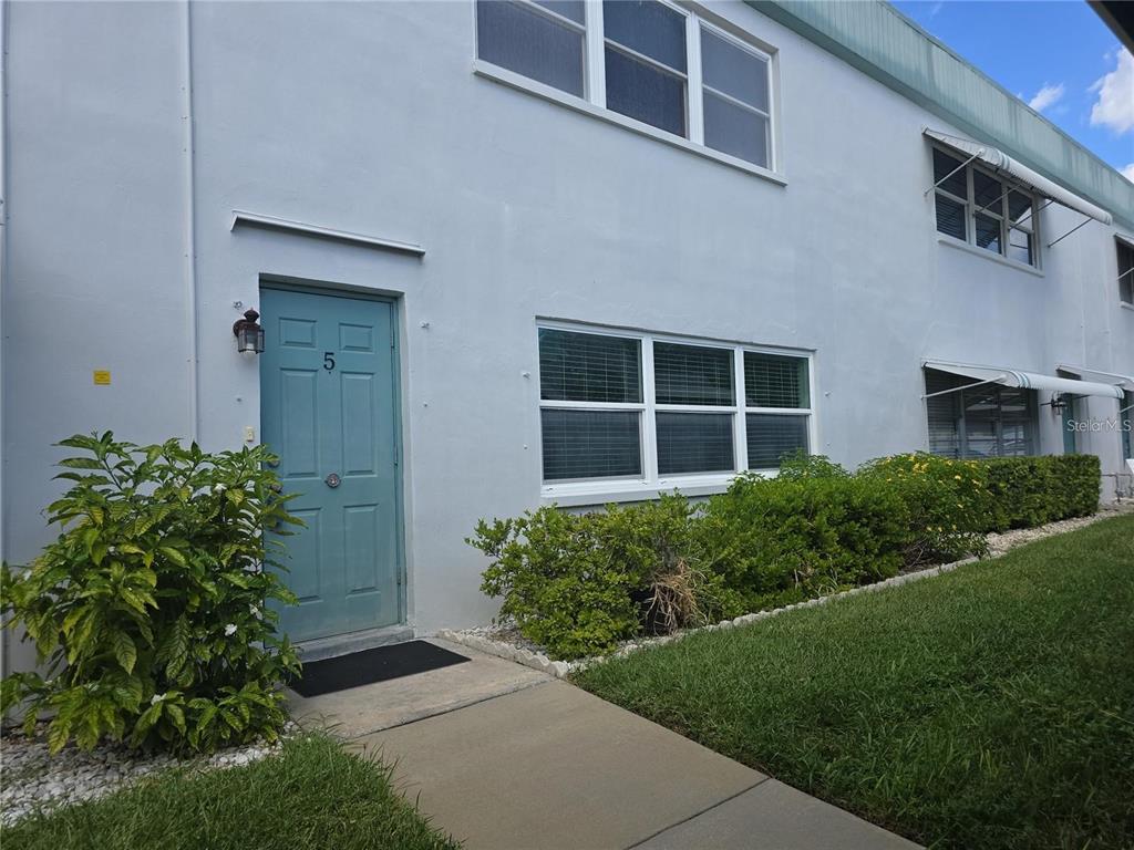 A light blue exterior wall features a teal front door labeled number five — 5267 81ST STREET N UNIT 5, ST PETERSBURG, FL