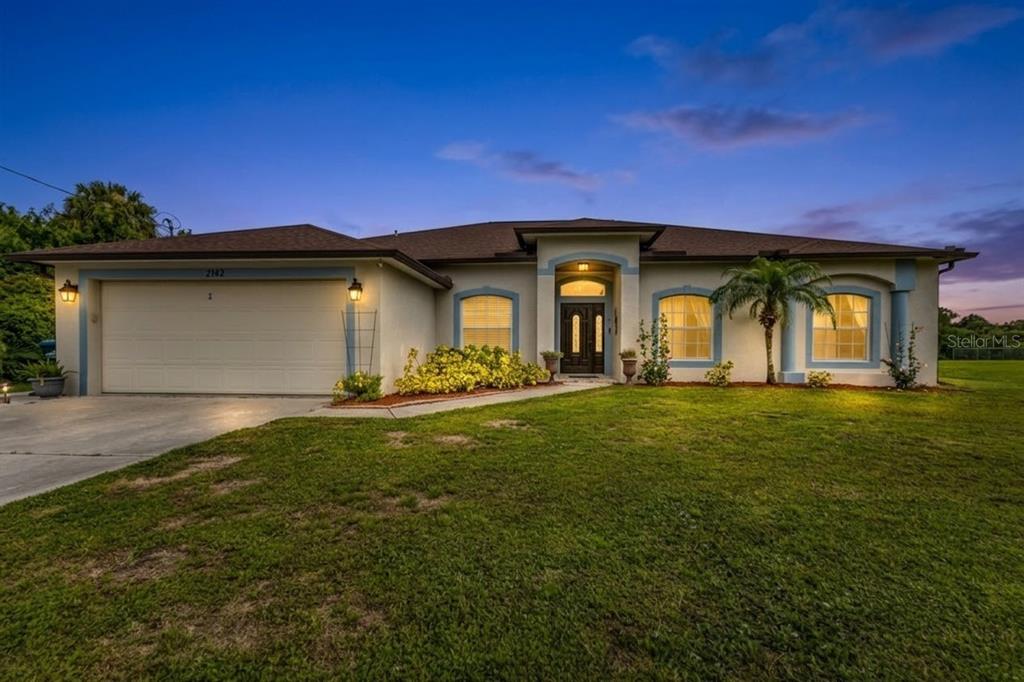 A single-story house with a two-car garage, arched windows, and a central entryway at dusk — 2142 SNOVER AVENUE, NORTH PORT, FL