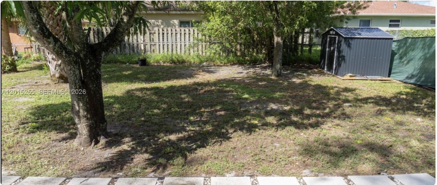 A grassy backyard features a metal storage shed, mature trees, and a wooden fence — 1019 NW 4th Ave, Pompano Beach FL 33060, POMPANO BEACH, FL