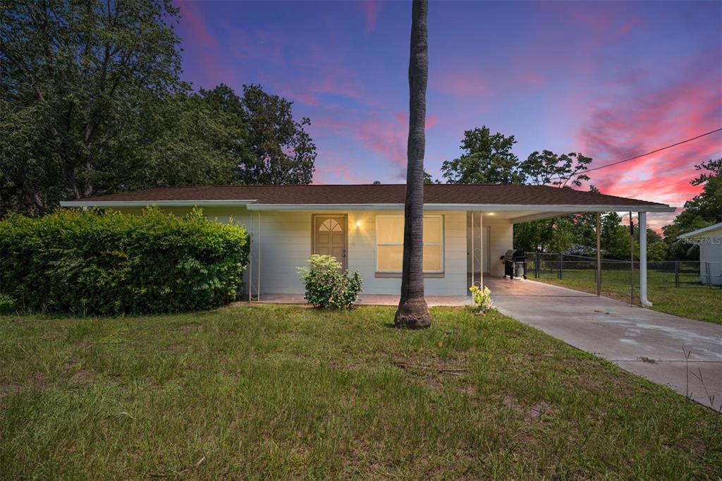 A single-story house with a carport and a palm tree in the front yard — 21545 SW HONEYSUCKLE STREET, DUNNELLON, FL