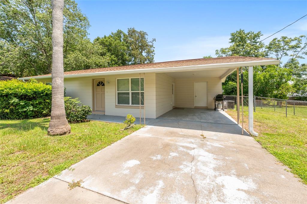 A single-story house with beige siding, a front carport, and a concrete driveway — 21545 SW HONEYSUCKLE STREET, DUNNELLON, FL