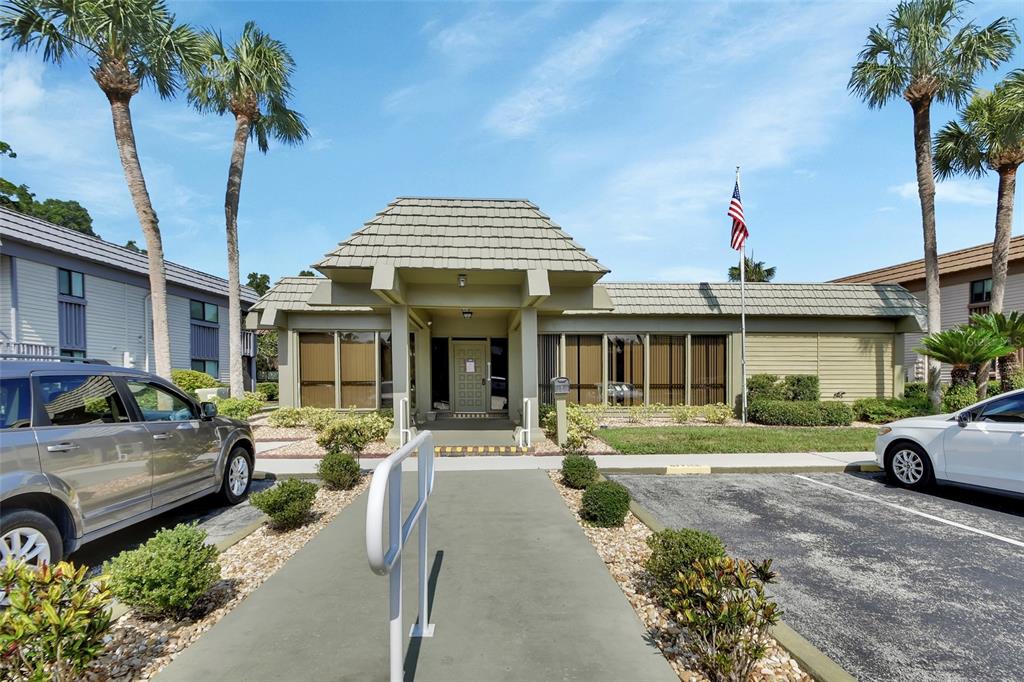 A single-story commercial building with a tan exterior, a shingled roof, and a paved walkway — 600 N BOUNDARY AVENUE UNIT 114A, DELAND, FL