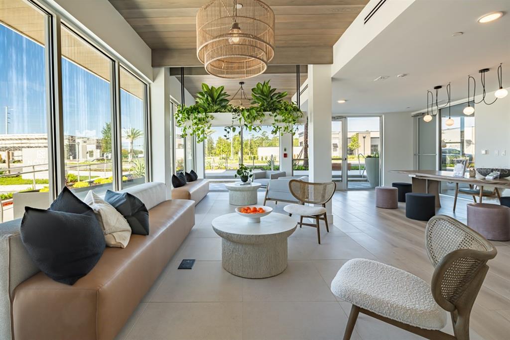 A modern lounge area features a tan sofa, round coffee tables, and a hanging planter — 11929 PIONEERS WAY UNIT C3.10, ORLANDO, FL