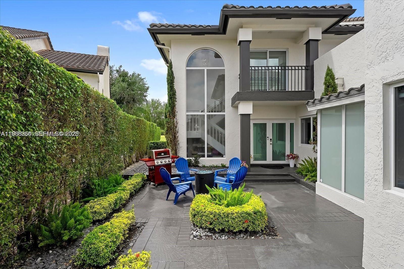 A patio features blue Adirondack chairs, a fire pit, and a red grill near a house — 22818 El Dorado Dr, Boca Raton FL 33433, BOCA RATON, FL