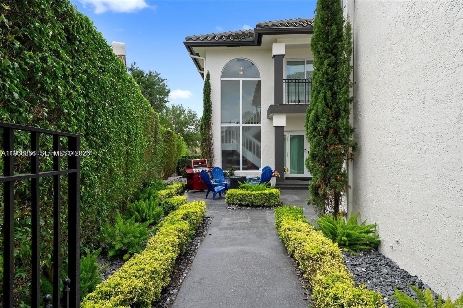 A paved walkway leads to a patio with blue chairs beside a two-story house — 22818 El Dorado Dr, Boca Raton FL 33433, BOCA RATON, FL