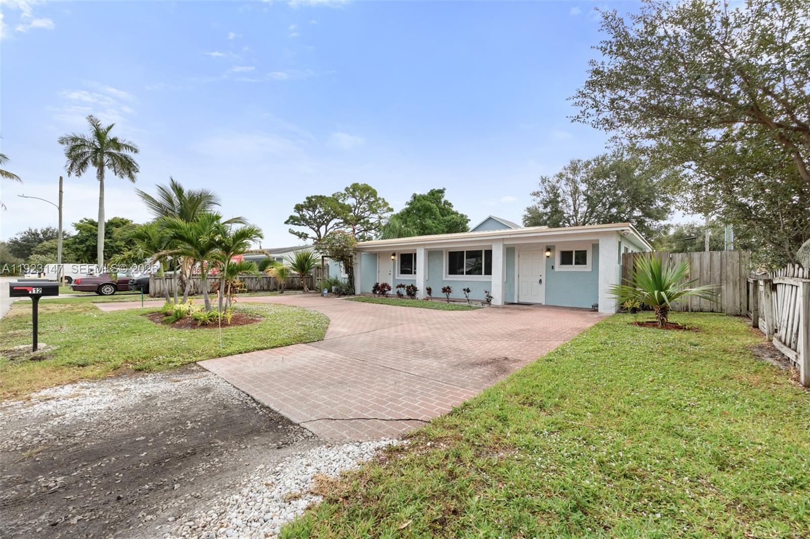 A light blue single-story house features a brick driveway and a palm-lined front yard — 112 Milton St, Lantana FL 33462, LANTANA, FL
