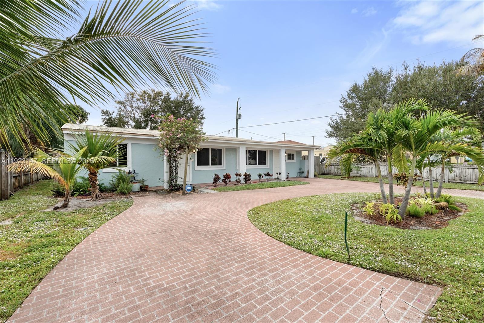 A light blue single-story house features a brick driveway and several palm trees — 112 Milton St, Lantana FL 33462, LANTANA, FL