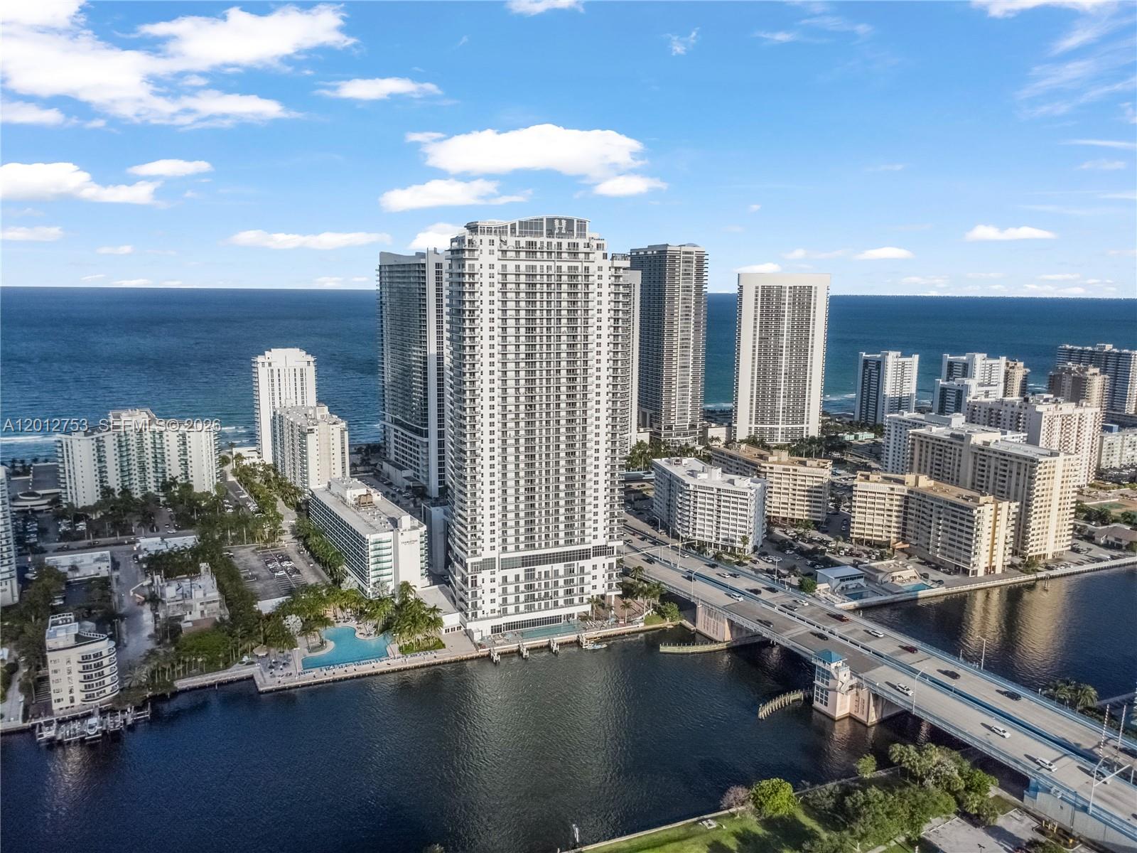 An aerial view shows a tall residential skyscraper near a bridge and the ocean — 4010 S Ocean Dr # R1801, Hollywood FL 33019, HOLLYWOOD, FL