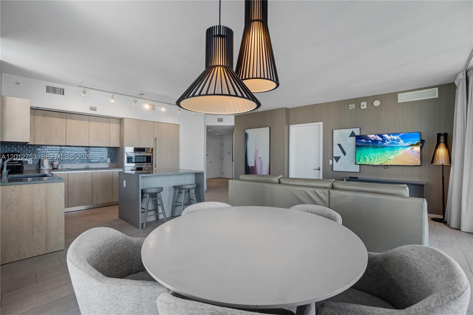 A modern open-concept living area features a kitchen, dining table, and a gray sofa — 4010 S Ocean Dr # R1801, Hollywood FL 33019, HOLLYWOOD, FL