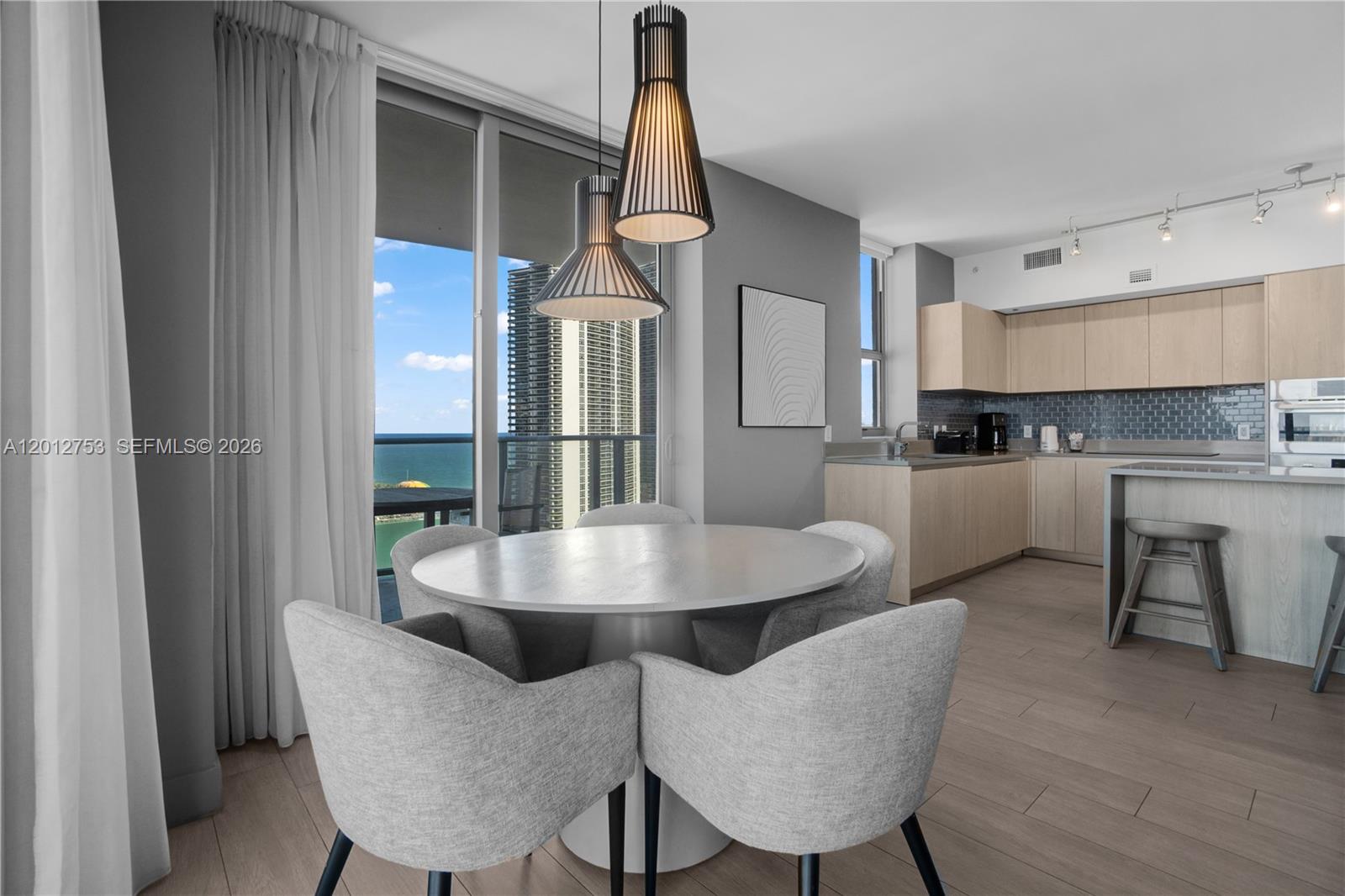 A dining area with a round table and chairs sits adjacent to a modern kitchen — 4010 S Ocean Dr # R1801, Hollywood FL 33019, HOLLYWOOD, FL
